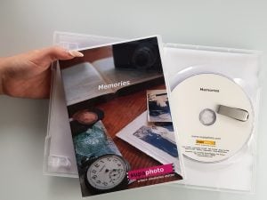 Hand holding two DVD cases with a disk and memory stick in it.