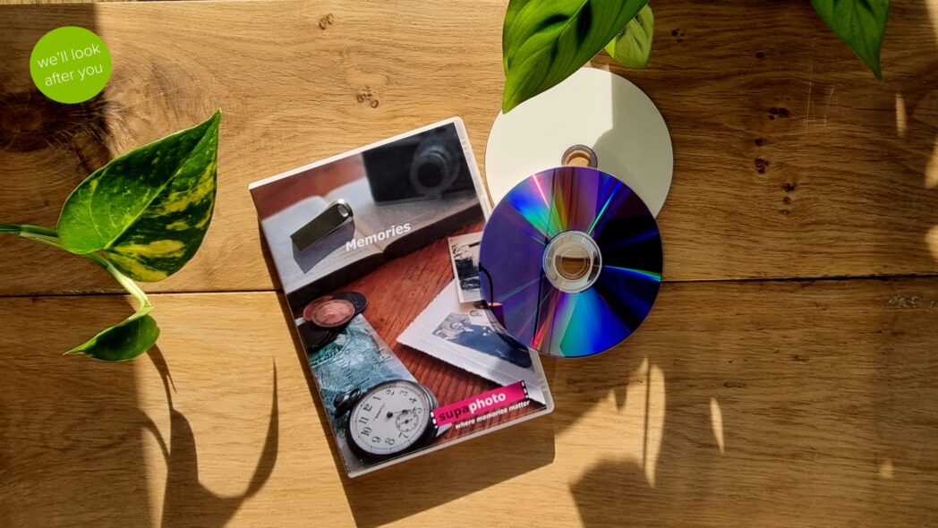 a couple of dvds with their case and a memory stick over a leaf and wood background