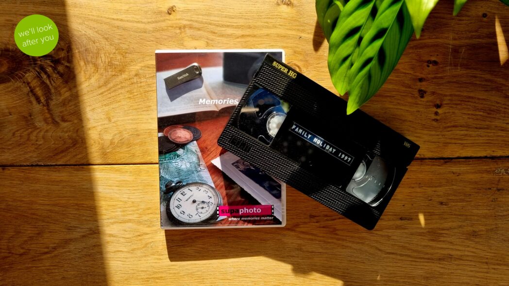 single vhs tape placed on a dvd case and memory stick that are on a wooden table