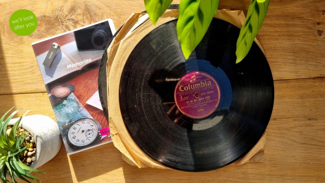 vinyl record with a dvd case and a silver memory stick displayed on a wooden table