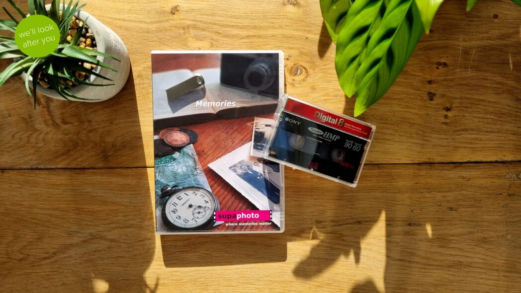 Digital 8 tape on a dvd case with a memory stick and a plant pot and wooden background