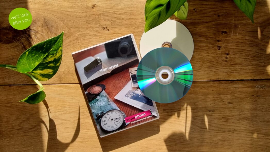 two CDs with a dvd case and a memory stick which are shown over a wooden background