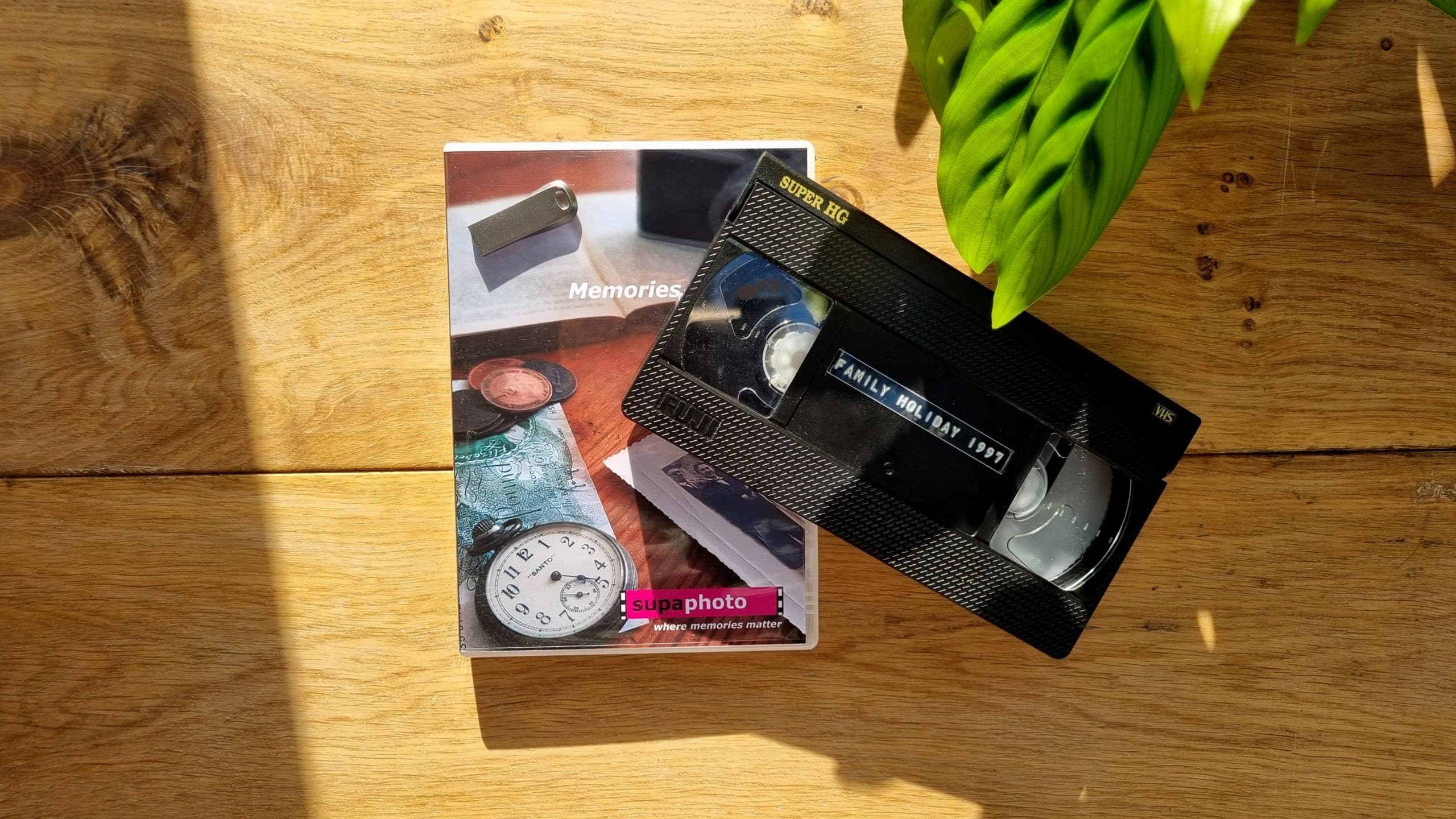 old video tape placed over a dvd and memory stick that are shown with a wooden table behind