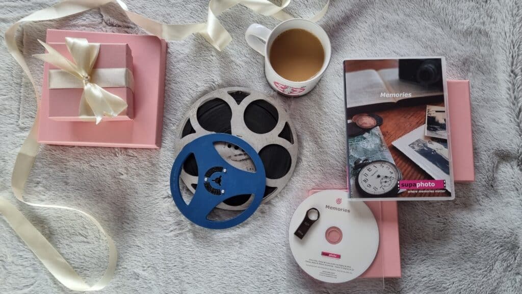 Cine reels, a cup of tea, a dvd disk and present boxes laid out on a soft carpet