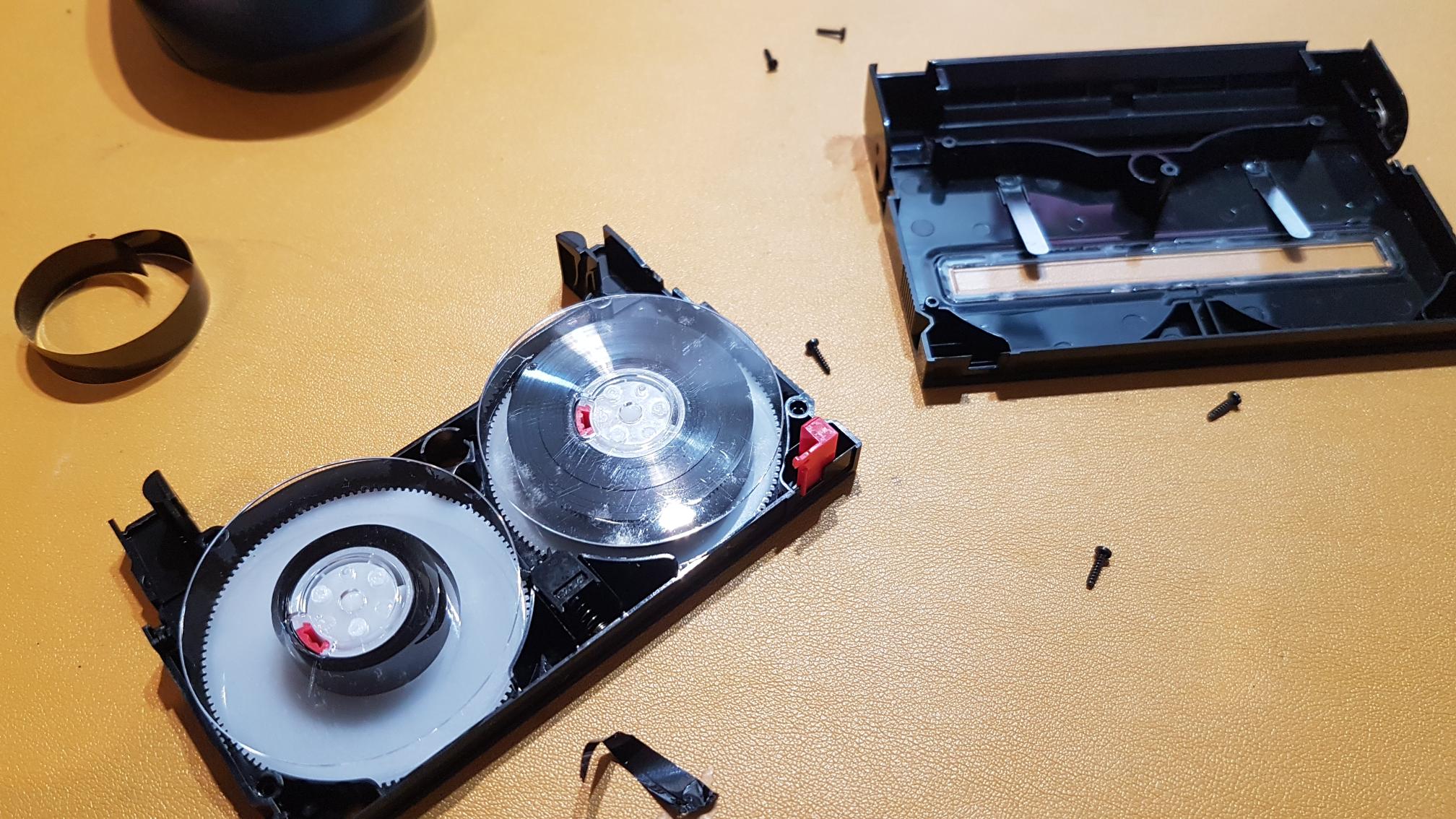 Broken Hi8 tape on a table with scattered parts.