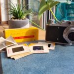 Camera, photo slides and kodak box resting on a table.