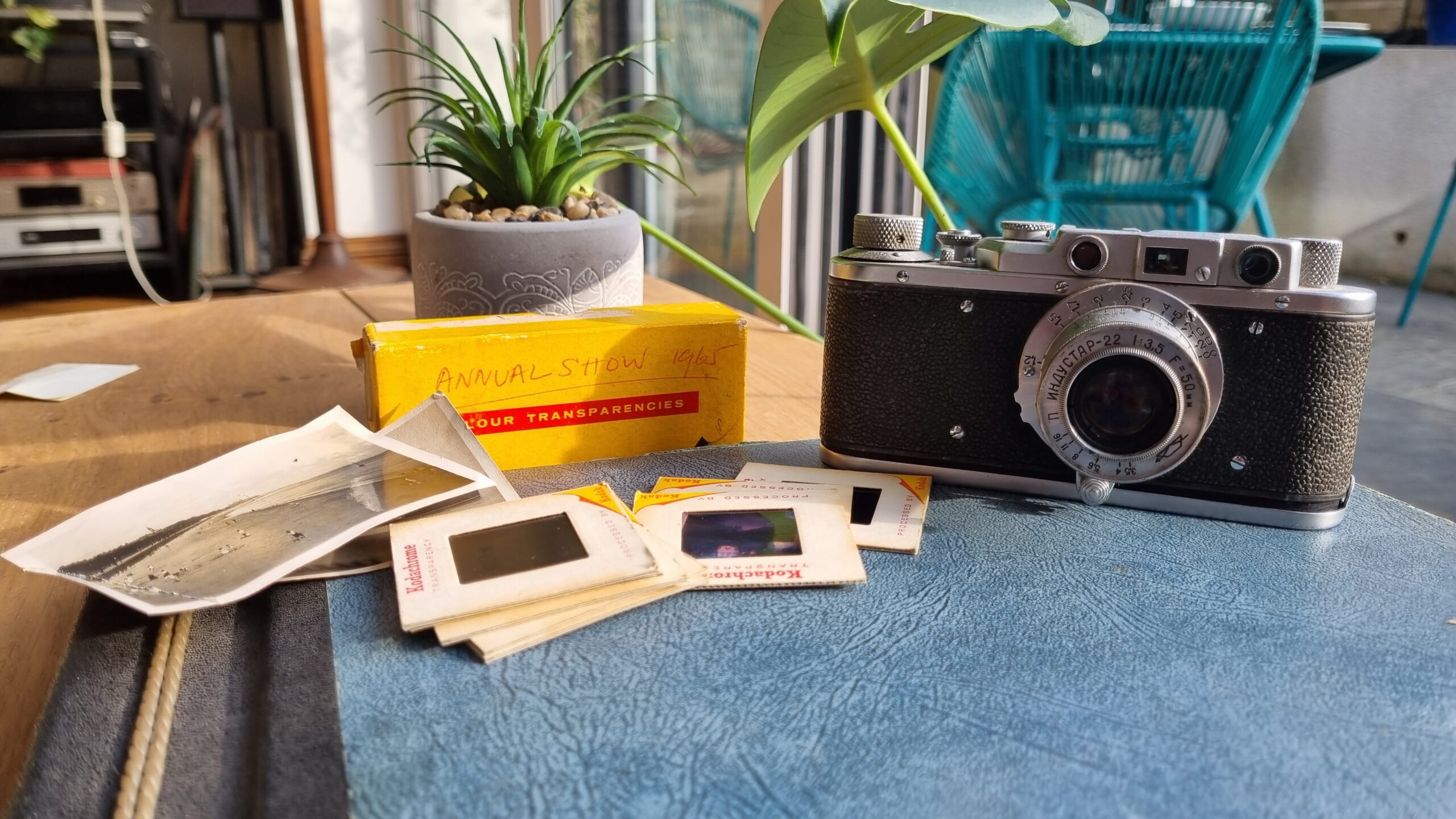 Camera, photo slides and kodak box resting on a table.