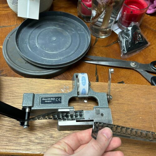 Image of cine film splicing being done on a wooden table with flowers in the background.