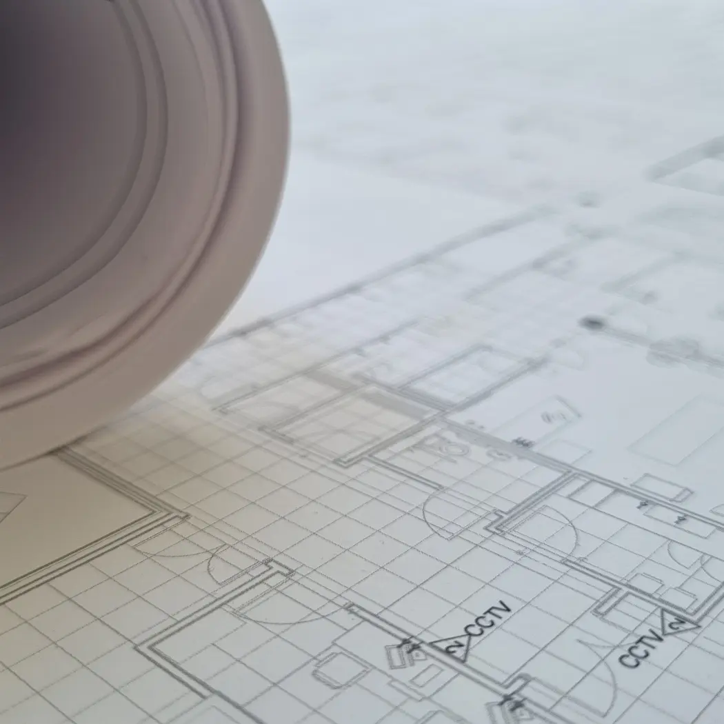 Rolled architectural plans resting on a detailed floor-plan drawing.