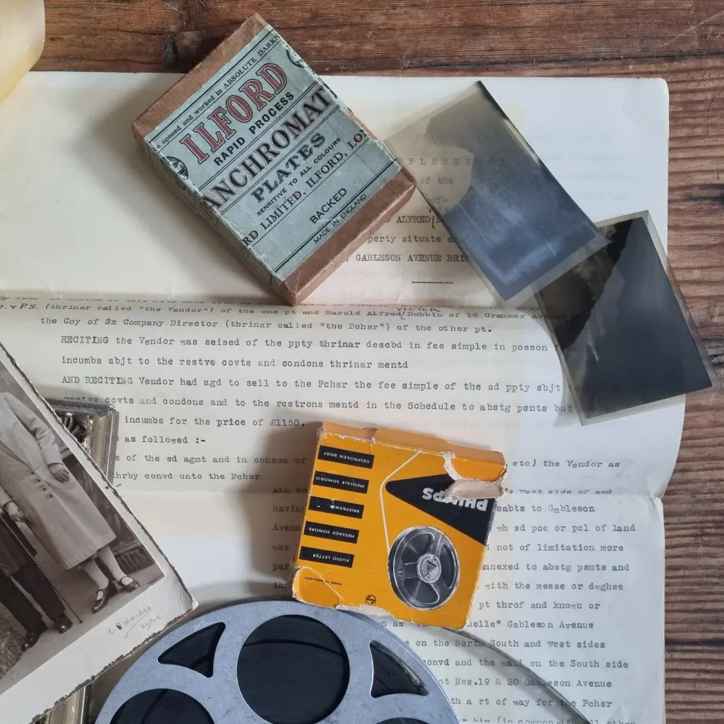 Vintage photographic materials, film reels, negatives, and documents arranged on a wooden table.