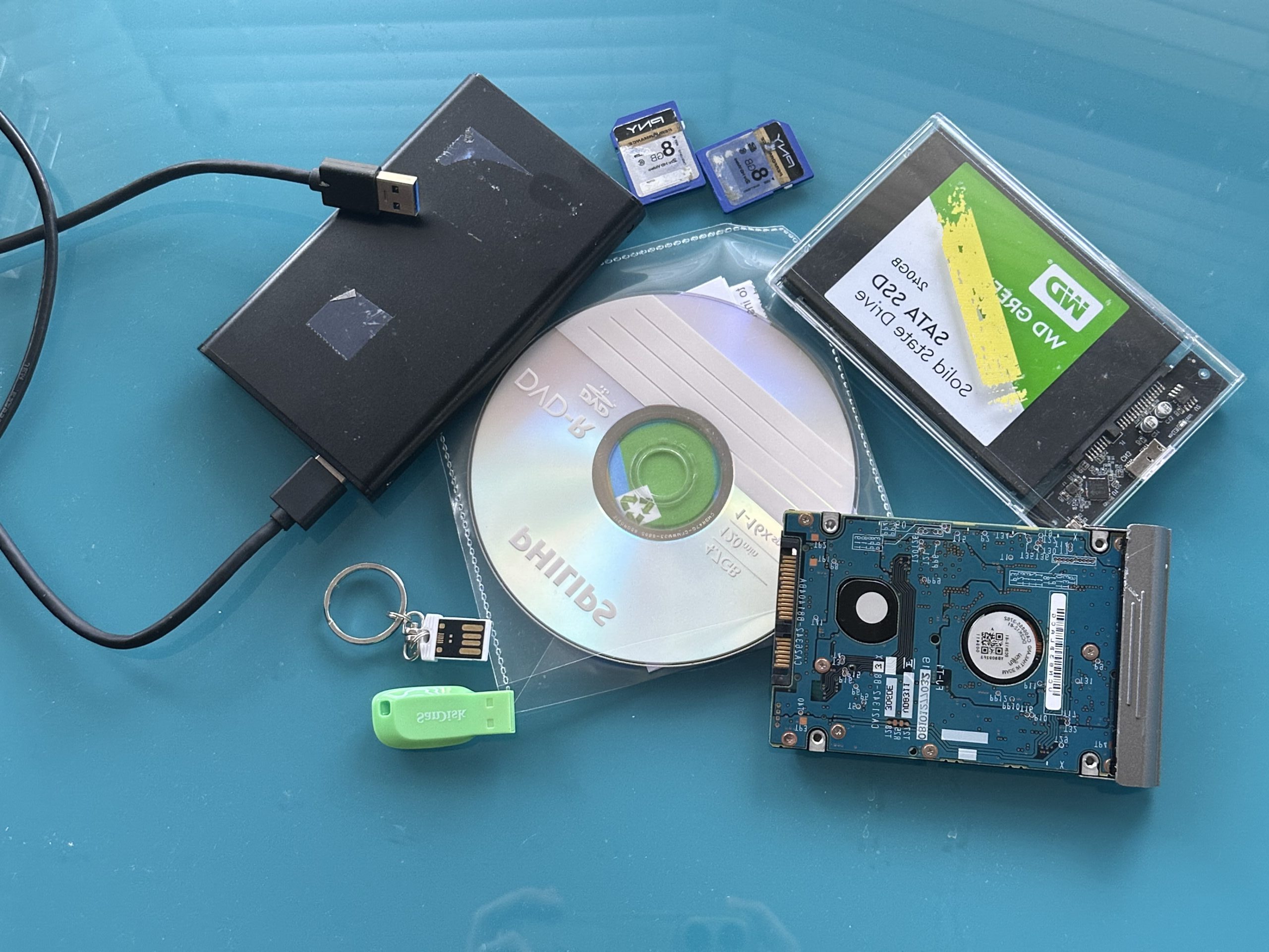 Hard Drive, USB stick, SD card, layed out on the table.